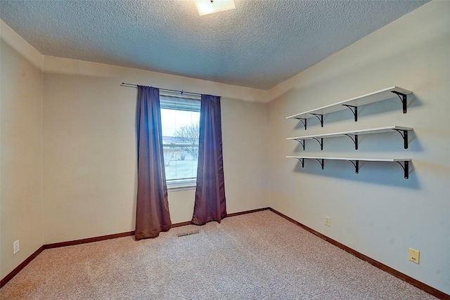 carpeted empty room with a textured ceiling