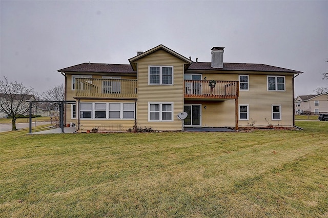 back of property with a balcony, a patio, and a lawn