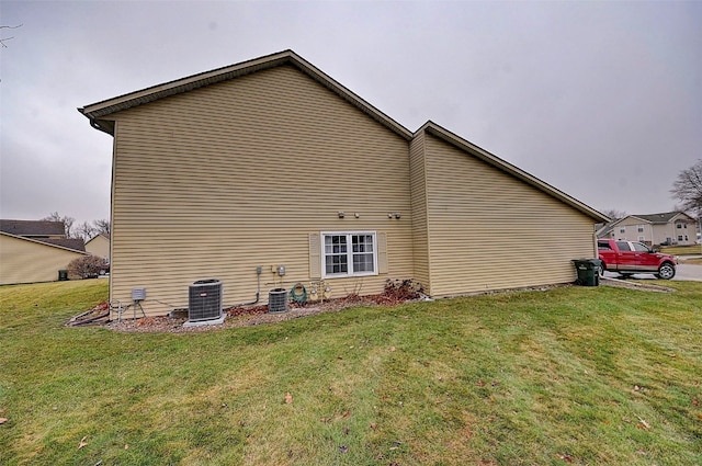 view of side of home with a yard and central AC