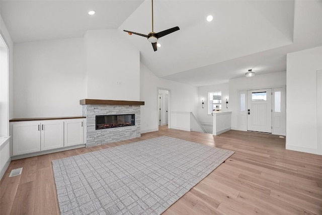 unfurnished living room featuring ceiling fan, a fireplace, high vaulted ceiling, and light wood-type flooring