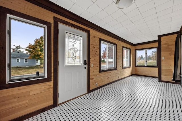 interior space with crown molding, plenty of natural light, and wooden walls