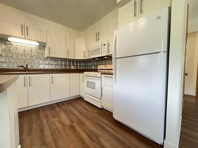 kitchen with white appliances, dark hardwood / wood-style flooring, sink, and white cabinets