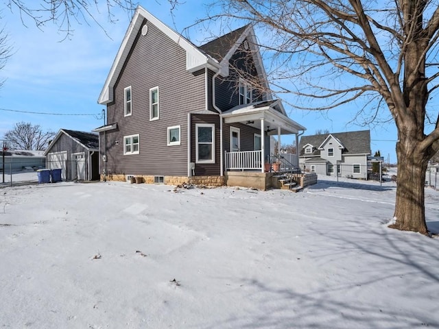 view of snowy exterior featuring a porch and an outdoor structure