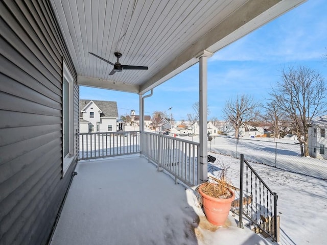 snow covered patio with ceiling fan and a porch