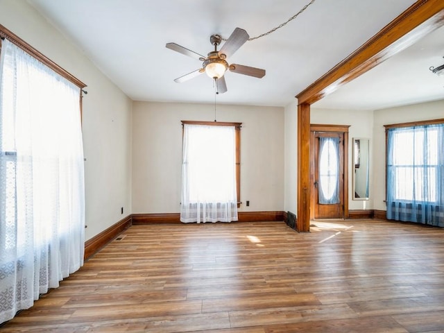 empty room featuring a ceiling fan, baseboards, and wood finished floors