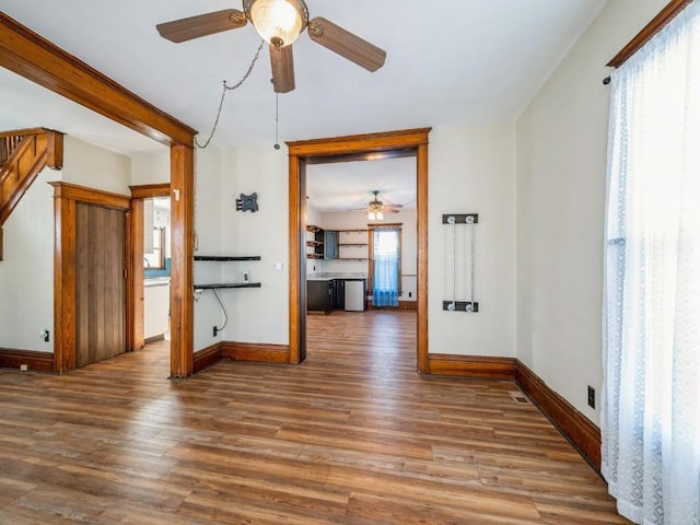 unfurnished room with stairway, baseboards, and wood finished floors