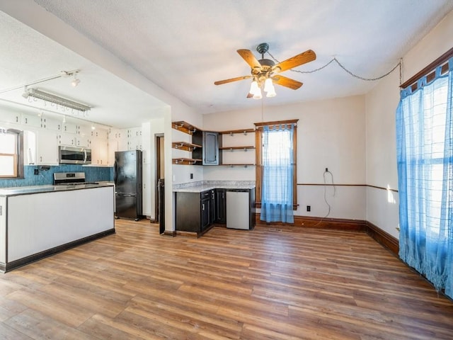 kitchen with stainless steel appliances, open shelves, wood finished floors, and a healthy amount of sunlight