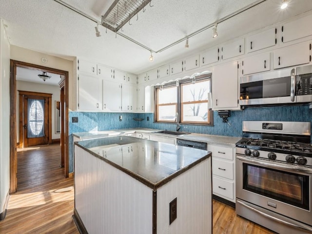 kitchen with appliances with stainless steel finishes, plenty of natural light, a kitchen island, and white cabinetry