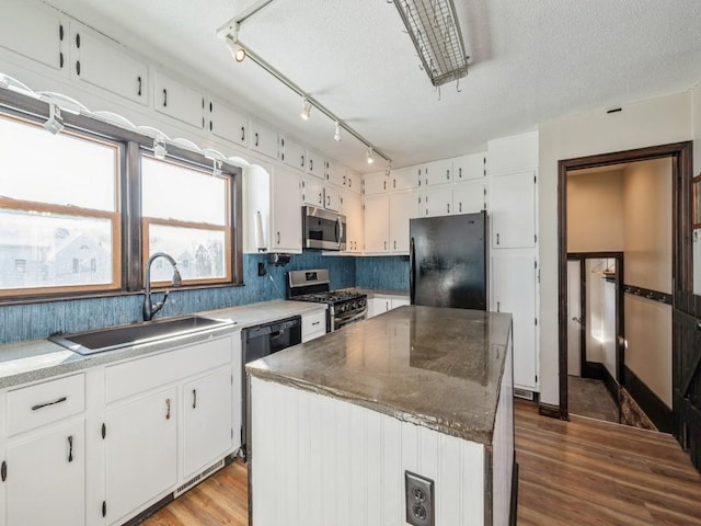 kitchen with wood finished floors, a kitchen island, a sink, white cabinets, and black appliances