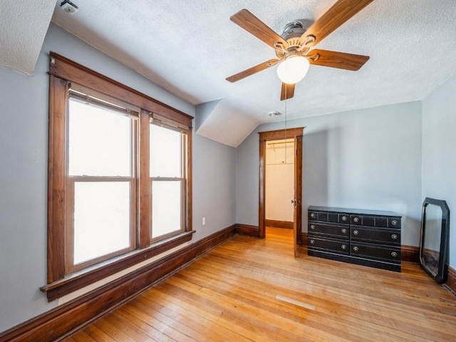 additional living space with ceiling fan, lofted ceiling, light hardwood / wood-style floors, and a textured ceiling