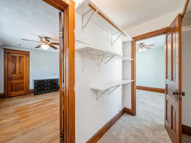 walk in closet with light carpet and ceiling fan