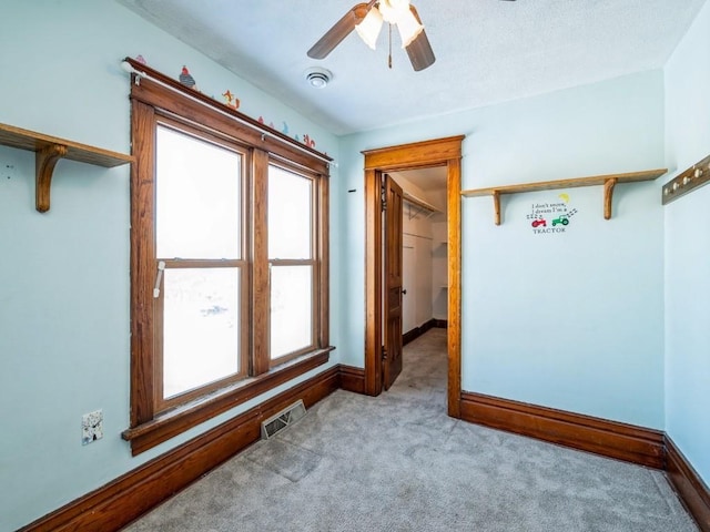 carpeted spare room with a ceiling fan, visible vents, and baseboards