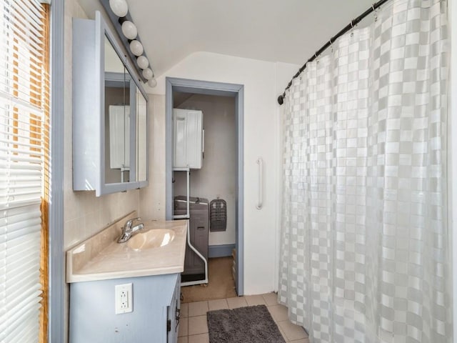 bathroom featuring tile patterned flooring, vanity, and vaulted ceiling