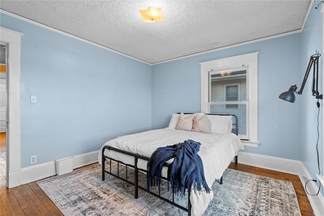 bedroom with ornamental molding, wood-type flooring, and a textured ceiling