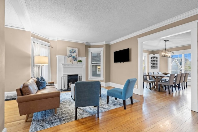 living room with ornamental molding, hardwood / wood-style floors, a notable chandelier, and a textured ceiling