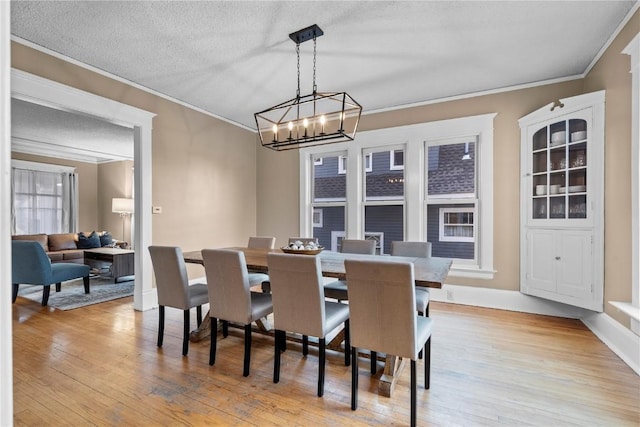 dining room with crown molding, a notable chandelier, light hardwood / wood-style flooring, and a textured ceiling