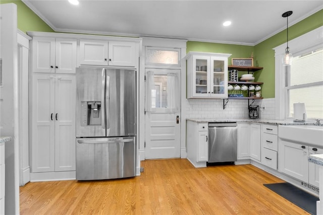 kitchen featuring stainless steel appliances, white cabinets, backsplash, and decorative light fixtures