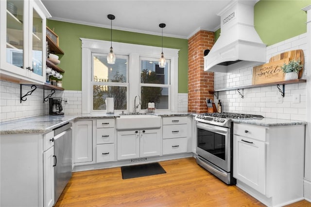 kitchen with premium range hood, sink, white cabinetry, tasteful backsplash, and appliances with stainless steel finishes