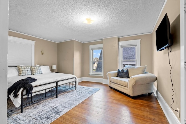 bedroom with hardwood / wood-style floors, ornamental molding, and a textured ceiling