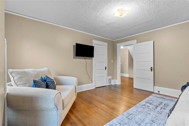 sitting room featuring wood-type flooring, ornamental molding, and a textured ceiling