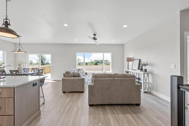 living room featuring ceiling fan, plenty of natural light, and light hardwood / wood-style floors