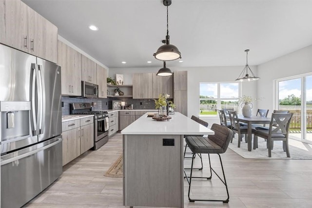 kitchen with a kitchen island, appliances with stainless steel finishes, pendant lighting, and decorative backsplash