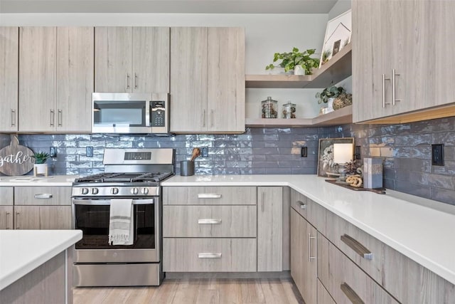 kitchen featuring stainless steel appliances, light brown cabinetry, light hardwood / wood-style flooring, and backsplash