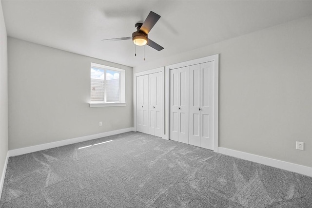 unfurnished bedroom featuring carpet, two closets, and ceiling fan