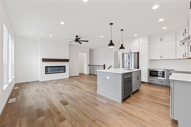 kitchen featuring gray cabinets, pendant lighting, sink, a kitchen island with sink, and stainless steel appliances