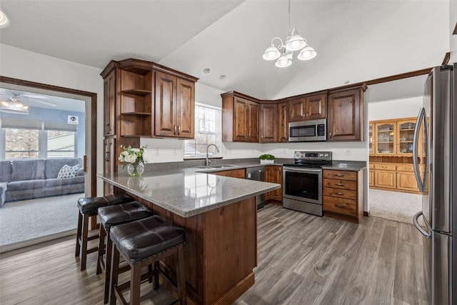 kitchen featuring appliances with stainless steel finishes, lofted ceiling, sink, a breakfast bar area, and kitchen peninsula