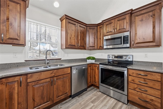 kitchen with appliances with stainless steel finishes, light hardwood / wood-style floors, and sink