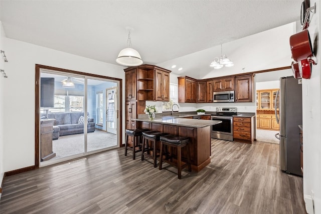 kitchen featuring hanging light fixtures, vaulted ceiling, a kitchen breakfast bar, and appliances with stainless steel finishes