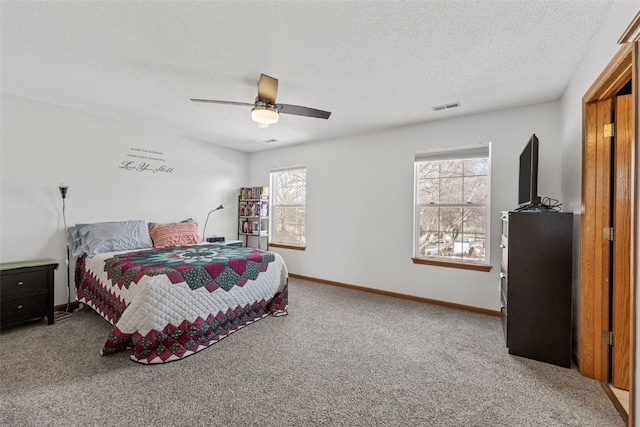 carpeted bedroom featuring ceiling fan and a textured ceiling