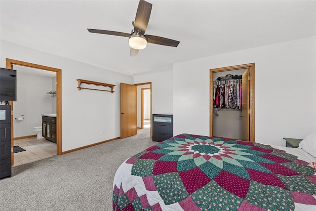 carpeted bedroom with ceiling fan, a walk in closet, ensuite bathroom, and a closet