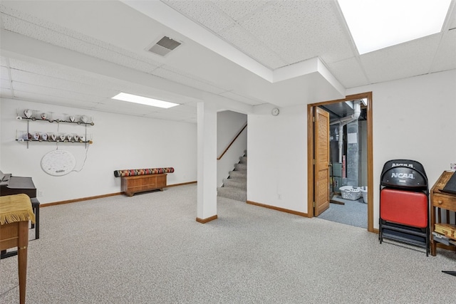 living area with a drop ceiling and carpet