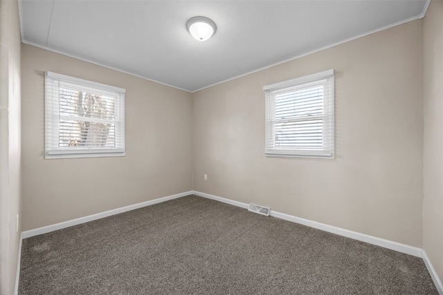 spare room featuring crown molding and dark colored carpet