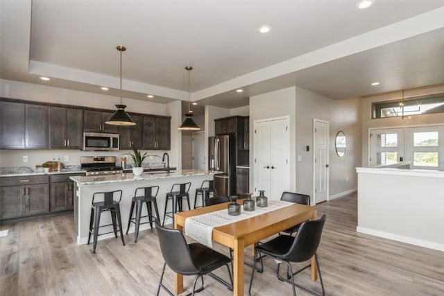 dining space featuring french doors, light wood-type flooring, and a tray ceiling