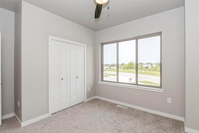 unfurnished bedroom featuring light carpet, ceiling fan, and a closet