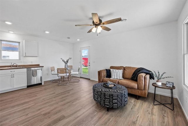 living room featuring ceiling fan, light hardwood / wood-style floors, and sink