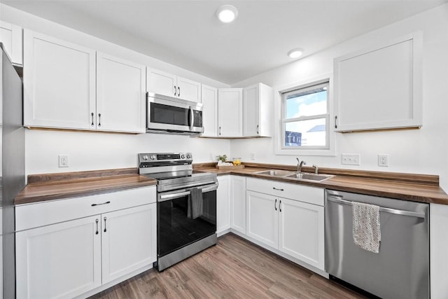 kitchen with butcher block counters, sink, white cabinets, and appliances with stainless steel finishes