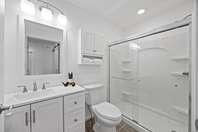 bathroom featuring a shower with door, vanity, tile patterned flooring, and toilet