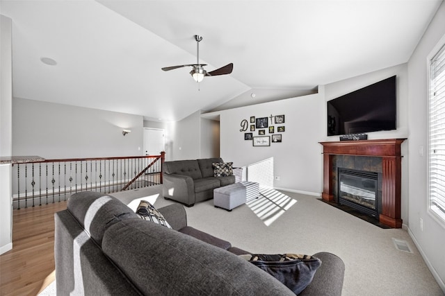 living room featuring ceiling fan, vaulted ceiling, a tile fireplace, and a wealth of natural light