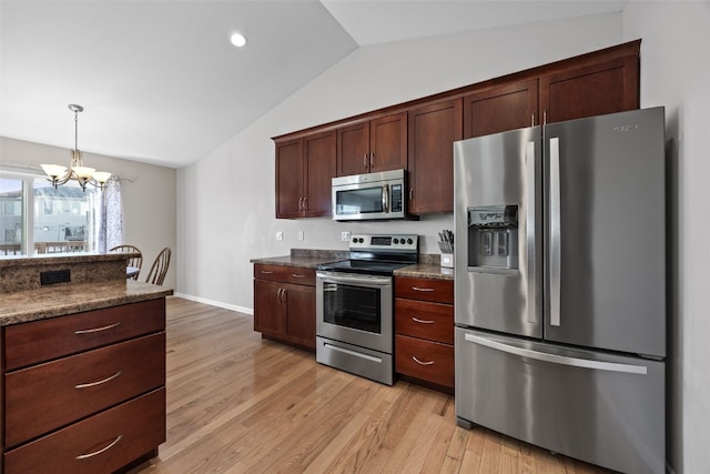 kitchen featuring pendant lighting, lofted ceiling, dark stone countertops, stainless steel appliances, and light hardwood / wood-style flooring