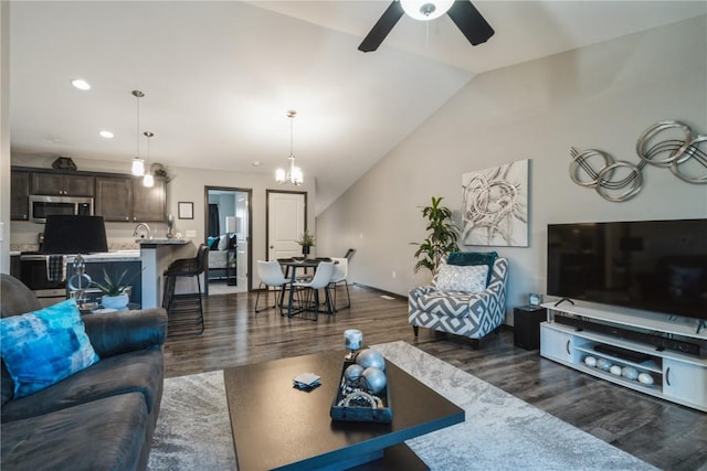 living room with lofted ceiling, dark wood-type flooring, ceiling fan with notable chandelier, and sink