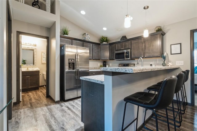 kitchen featuring a kitchen bar, dark brown cabinets, kitchen peninsula, and appliances with stainless steel finishes