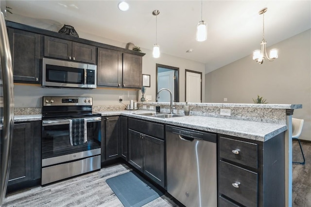 kitchen with appliances with stainless steel finishes, decorative light fixtures, kitchen peninsula, and sink