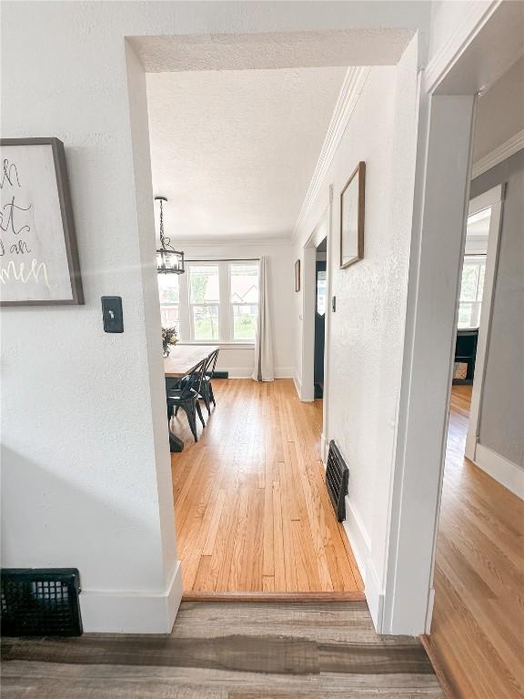 hall featuring crown molding, a chandelier, and hardwood / wood-style flooring