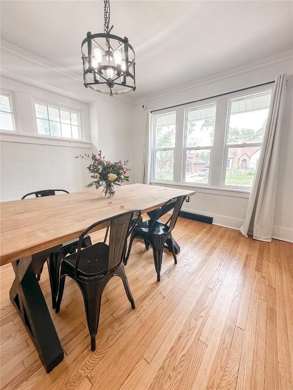 dining space with crown molding, a chandelier, and light wood-type flooring