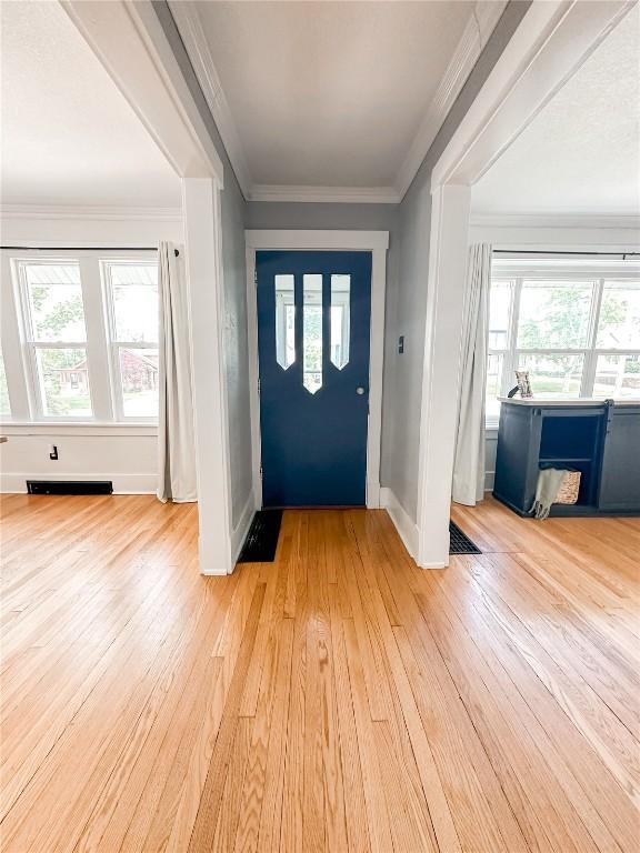 entryway featuring crown molding and light wood-type flooring