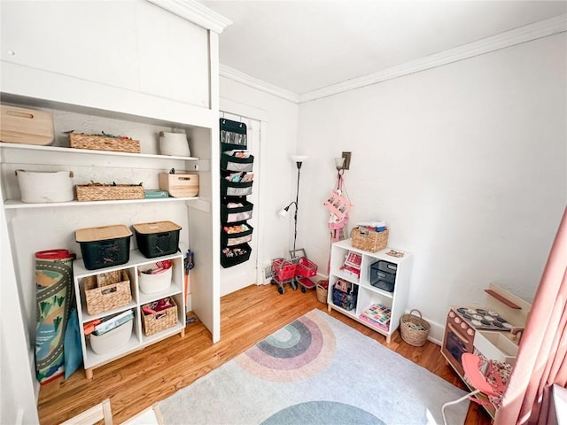 rec room with wood-type flooring and ornamental molding